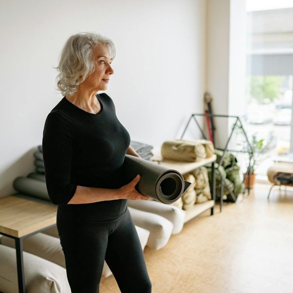 Person meditating on a yoga mat in a bright, airy room.